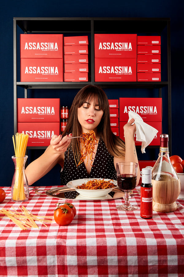 donna che mangia un piatto di spaghetti all'assassina